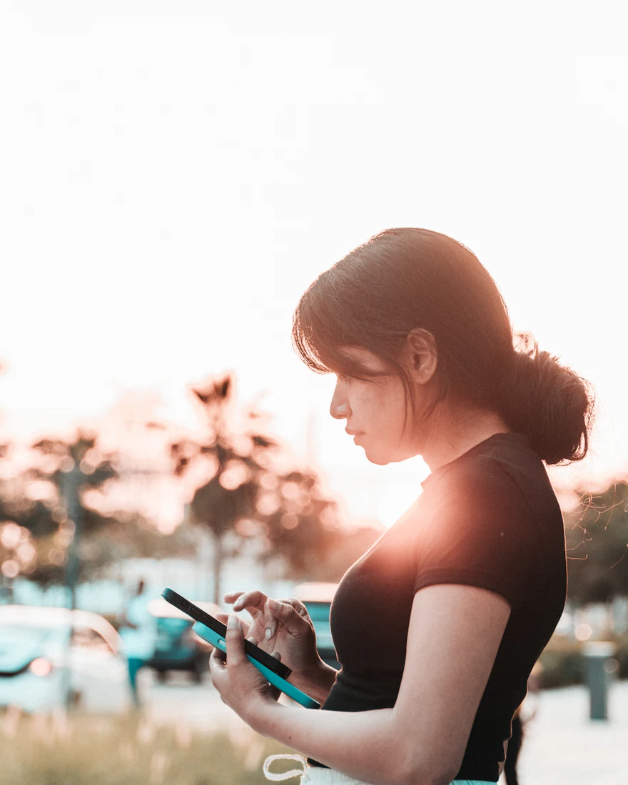 Vrouw kijkt op haar telefoon in fel tegenlicht